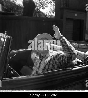 Åke Söderblom 1910-1965, acteur suédois ici pendant le tournage du film The Happy Shoemaker dans le rôle de l'agent aspirateur Gotte Jönshammar. Ici, dans sa voiture ouverte, un cabriolet où il lève la main pour saluer. Le film a été présenté en première suédoise le 19 septembre 1955 à l'Olympia de Stockholm en Suède. Banque D'Images