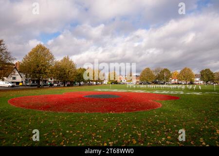 Wooburn Green, Royaume-Uni. 9 novembre 2023. Un magnifique énorme cypher de coquelicot a été peint sur le vert du village à Wooburn Green, Buckinghamshire avant le jour de l'Armistice et le dimanche du souvenir ce week-end avec les mots Wooburn Green We Will Remember. Prenant trois heures pour terminer, le coquelicot de 10 pieds a été conçu et peint par le gardien de sol local et gestionnaire des contrats à Groundtel, Danny Perkins. Les 1st Wooburn Scouts ont également placé 146 croix commémoratives à côté du coquelicot en mémoire des villageois morts pendant la première et la Seconde Guerre mondiale. Crédit : Maureen McLean/Alamy Live News Banque D'Images