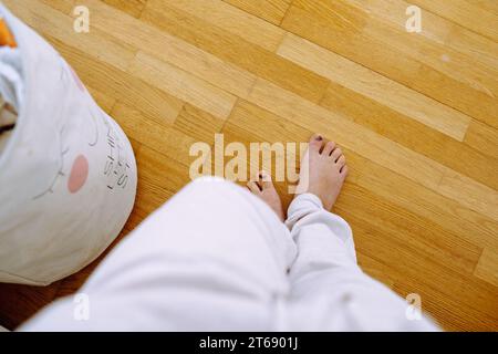 Vue de dessus jambes féminines pieds nus sur plancher en bois stratifié Banque D'Images