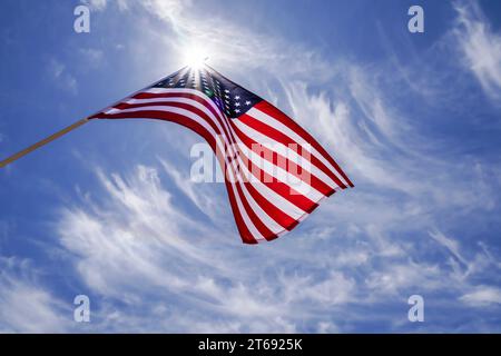 Drapeau américain agitant dans un ciel bleu de nuages striés avec une étoile derrière le drapeau américain. L'étoile nationale rouge, blanche et bleue a piqué le drapeau américain volant haut. Banque D'Images