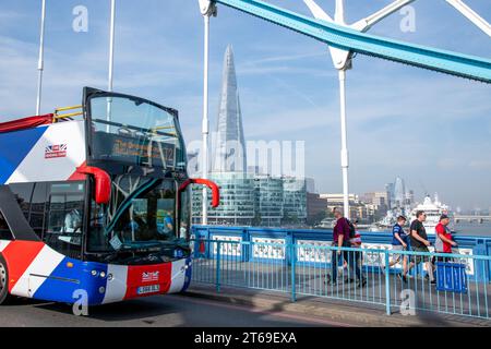 Un bus touristique voyage à travers Tower Bridge à Londres aux côtés d'un groupe de personnes avec le gratte-ciel Shard vu en arrière-plan Banque D'Images