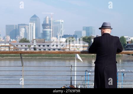 Un homme regarde au-dessus de la Tamise à Greenwich, Londres vers les gratte-ciel des Docklands Banque D'Images