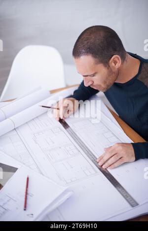 Vérifier son travail pour assurer le plus haut niveau. Prise de vue en grand angle d'un architecte qui rédige des plans de construction. Banque D'Images