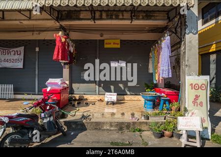 Robes sur l'affichage dans le magasin de vêtements de détail avec signe rappelant aux clients de s'il vous plaît enlever vos chaussures à Chiang Rai, Thaïlande Banque D'Images