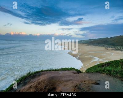 Cette image dispose d'un banc extérieur situé près d'un front de mer au crépuscule, donnant sur une plage magnifique Banque D'Images