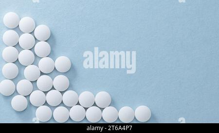Pilules blanches ou capsules se trouve dans les rangées sur fond bleu Banque D'Images