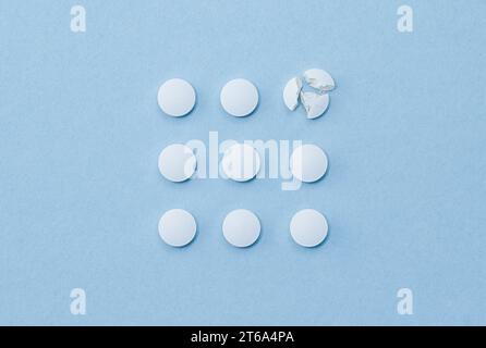 Pilules rondes blanches disposées dans l'ordre carré et l'une d'entre elles est écrasée sur des pièces. Banque D'Images