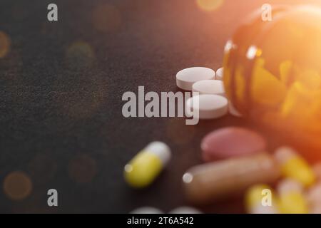 Diverses pilules renversant hors d'une bouteille de pilule rouge vif orange. Banque D'Images