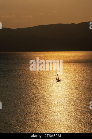 Voilier, dans le lac. Vie d'aventure. Lueur dorée dans l'eau. Tout nouveau jour, concept. Silhouette. Ohrid Macédoine été 2023. Banque D'Images