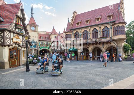 Les clients du parc masqué marchent et font du scooter à travers le pavillon allemand d'Epcot au Walt Disney World à Orlando, en Floride Banque D'Images
