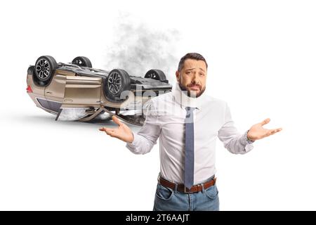 Conducteur malheureux après un accident de voiture devant un SUV à l'envers avec de la fumée et des fenêtres cassées isolé sur fond blanc Banque D'Images