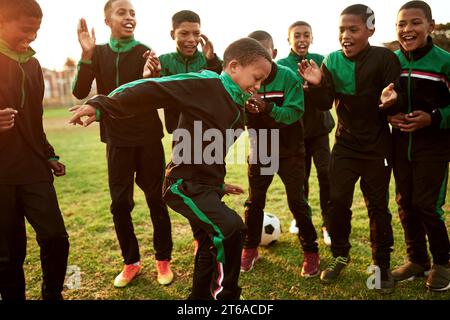 Le football est une activité tellement amusante à participer. une équipe de football de garçons encourageant leur coéquipier sur un terrain de sport. Banque D'Images