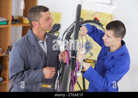 mécanicien stagiaire supervisé travaillant sur vélo en atelier Banque D'Images