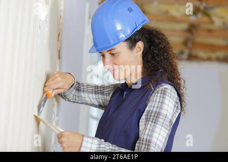 travailleur professionnel enlevant le papier peint du mur Banque D'Images