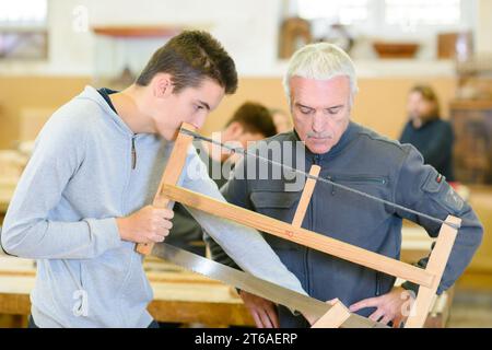 jeune homme apprend du maître luthier dans la leçon de scie Banque D'Images