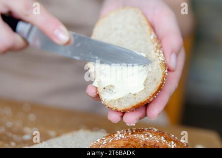 Gros plan des mains d'une femme étalant du beurre sur une tranche de pain. Restauration rapide pour la randonnée ou si vous n'avez pas le temps de faire de la nourriture. Banque D'Images