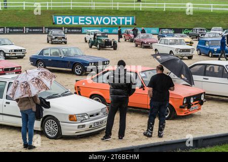 Chester, Cheshire, Angleterre, 1 octobre 2023. Les gens regardant une Ford Escort 1600 Sport orange et une Ford Sierra RS Cosworth blanche à une vente aux enchères de voitures. Banque D'Images