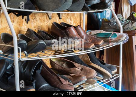 Rack en métal avec chaussures de femme usagées à vendre à l'intérieur du magasin de biens d'occasion et de biens meubles. Banque D'Images