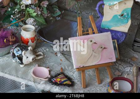 Peinture de colombes blanches, de fleurs en soie et de pièces en céramique à vendre à l'intérieur du magasin de biens d'occasion et de biens meubles. Banque D'Images