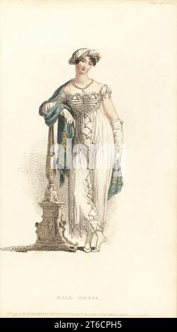 Régence femme en robe de bal et turban, 1813.Robe grecque de crêpe lilas, jupons de satin blanc, corsage de satin décoré de perles, turban indien de crêpe argentée dépolie, collier et médaillon de perles, pantoufles de satin, ventilateur d'ivoire, foulard de citron.Tôle 46, vol. 9, juin 1 1813.Gravure sur plaque de coperplate de couleur main par Thomas Uwins de Rudolph Ackermann's Repository of Arts, Londres. Banque D'Images