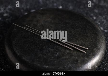 Aiguilles d'acupuncture et pierre de spa sur la table, gros plan Banque D'Images