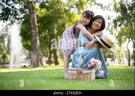 Une heureuse grand-mère asiatique aînée et sa petite-fille mignonne s'étreignent, apprécient les moments tendres et se câlinent tout en s'amusant Banque D'Images