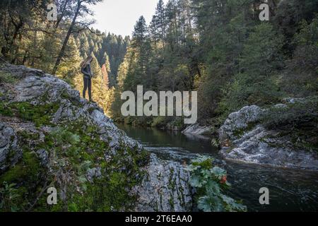 Un randonneur se dresse sur une formation rocheuse surplombant Butte Creek dans la nature sauvage de Californie. Banque D'Images
