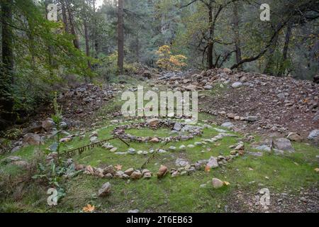 Art environnemental, un motif en spirale construit à partir de rochers dans la nature sauvage du comté de Butte, l'œuvre d'art en pierre se démarque dans la forêt. Banque D'Images