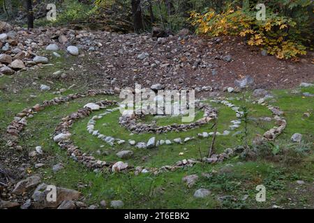 Art environnemental, un motif en spirale construit à partir de rochers dans la nature sauvage du comté de Butte, l'œuvre d'art en pierre se démarque dans la forêt. Banque D'Images