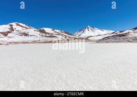 La glace solide du lac gelé, Laguna Miscanti, pendant l'hiver dans les Andes au nord du Chili. Les montagnes surplombent le lagon. Banque D'Images