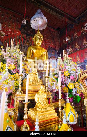 Une grande figure dorée de Bouddha assis, partie d'un autel avec des bougies blanches. Au Wat Saket, le Mont d'Or. À Bangkok, Thaïlande. Banque D'Images