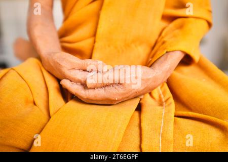 Statue miniature en cire représentant les mains serrées d'un vieux moine en robe orange. Au Wat Saket, le Mont d'Or. À Bangkok, Thaïlande. Banque D'Images