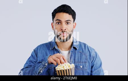 Télévision, portrait et homme avec pop-corn en studio pour film, film ou documentaire sur fond gris. Cinéma, regarder la télévision et visage de modèle avec Banque D'Images