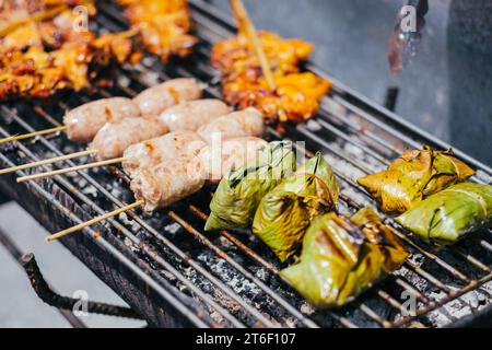 Griller diverses viandes sur des brochettes de bambou courtes et fines sur un feu ouvert ou un gril. Banque D'Images