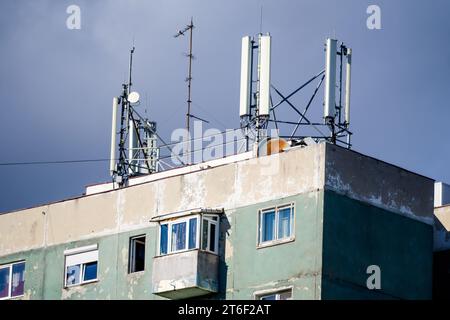 Antennes de télécommunications sur le toit d'un ancien bâtiment avec ciel bleu ciel nuageux en arrière-plan Banque D'Images