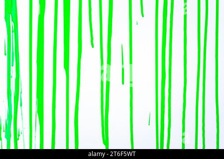 La peinture coule sur une surface vert clair. Un arrière-plan avec des bandes de couleur. Flux verticaux de peinture. Structure abstraite de fond Banque D'Images