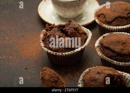 Muffins bruns au chocolat et au cacao avec cappuccino café dans la vue d'angle de tasse sur fond de pierre rustique brun, cupcakes doux au chocolat noir maison Banque D'Images