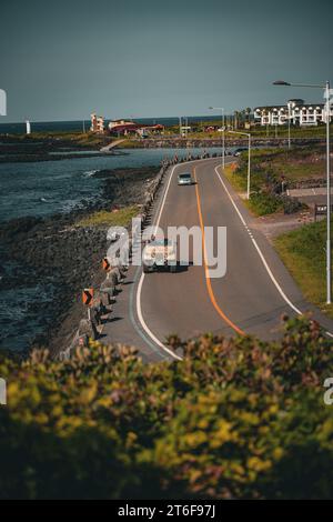 Une route panoramique avec plusieurs gros camions circulant le long d'un plan d'eau Banque D'Images