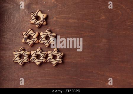 Forme d'arbre de Noël faite à partir de biscuits en forme d'étoile de pain d'épice avec du chocolat, bannière sur le fond en bois brun Banque D'Images