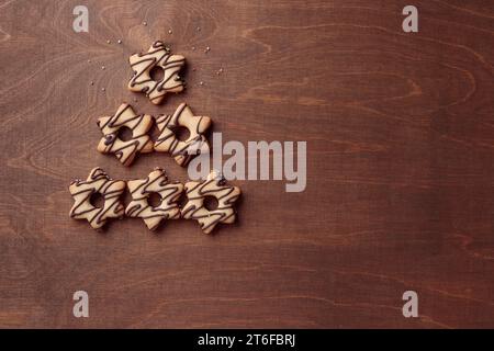 Forme d'arbre de Noël faite à partir de biscuits en forme d'étoile de pain d'épice avec du chocolat, bannière sur le fond en bois brun Banque D'Images