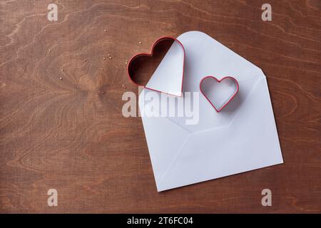 Deux emporte-pièces en forme de coeur sur le fond en bois brun foncé avec lettre, bannière horizontale, vue de dessus Banque D'Images