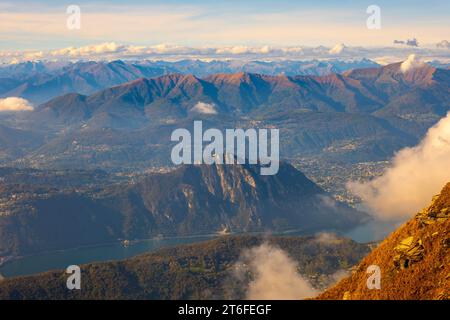 Vue aérienne sur le magnifique paysage montagneux avec des nuages et le lac de Lugano et la ville de Lugano dans une journée ensoleillée au Tessin, en Suisse Banque D'Images