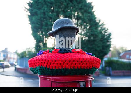 Un surmontoir de boîte aux lettres tricoté pour commémorer le jour de l'armistice est vu à Manchester, Royaume-Uni. Crédit : Jon Super/Alamy Live News. Banque D'Images