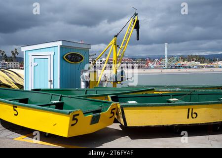 Santa Cruz, USA - 05,02,2023 : bateaux de couleur verte et jaune placés sur le remblai près de grue de chargeur marine pour le transport dans le port contre nuageux Banque D'Images