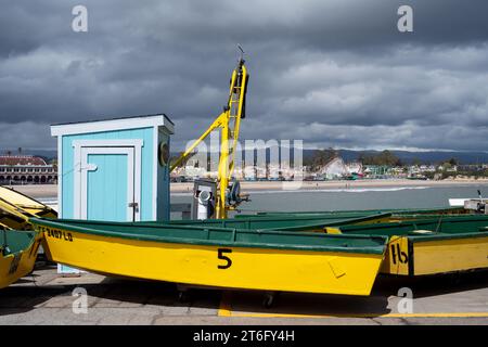 Santa Cruz, USA - 05,02,2023 : bateaux de couleur verte et jaune placés sur le remblai près de grue de chargeur marine pour le transport dans le port contre nuageux Banque D'Images