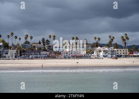 Santa Cruz, États-Unis - 05,02,2023 : Maisons situées parmi les palmiers tropicaux sur la plage de sable près de la mer ondulante sous un ciel nuageux orageux Banque D'Images
