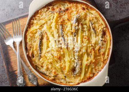 Tentation maison de Jansson faite à partir de pommes de terre, oignons et sprats gros plan sur le plat de cuisson sur la table. Vue de dessus horizontale Banque D'Images