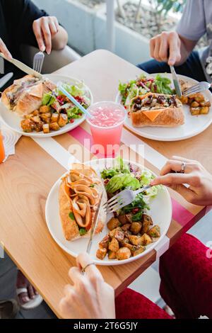 Trois personnes qui ont une nourriture décontractée se rencontrent en prenant des sanwiches et de la restauration rapide au cours du déjeuner. Banque D'Images