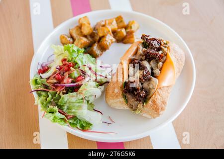 Sandwich ouvert au poulet dans du pain ciabatta servi avec des légumes sur le côté. Banque D'Images