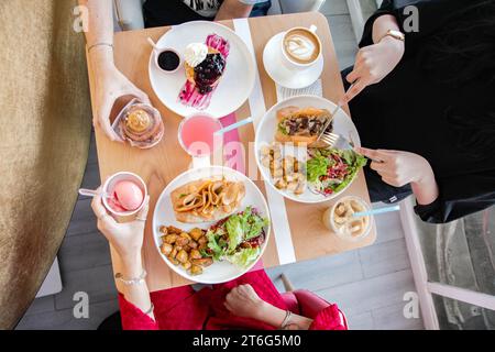 Trois personnes ayant une cuisine décontractée se rencontrent avec des glaces sanwiches et des desserts et de la restauration rapide au cours du déjeuner. Banque D'Images